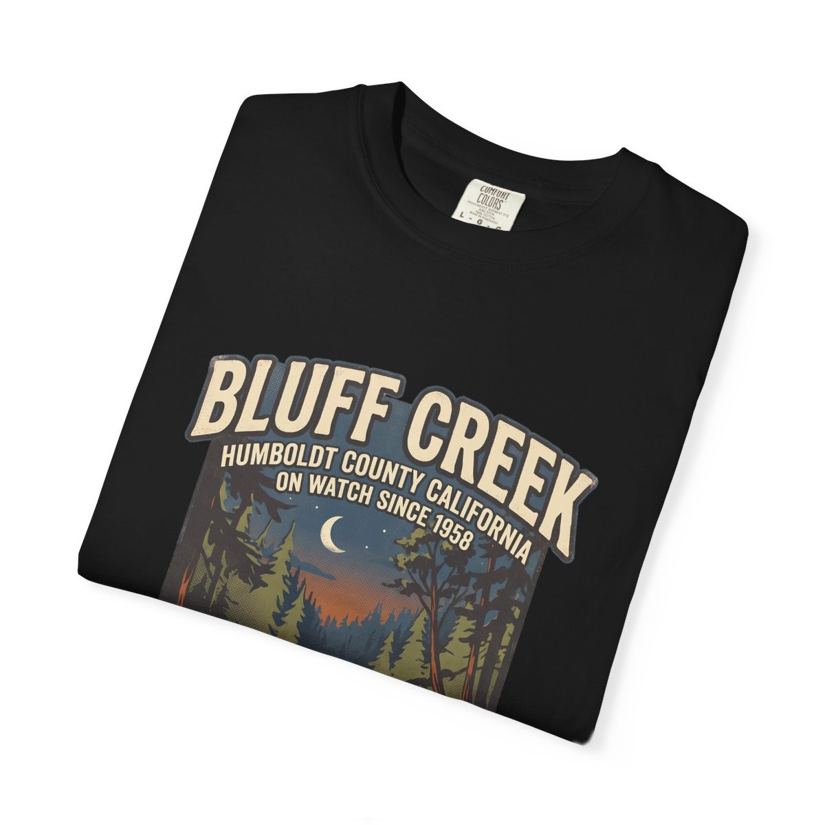 Close-up of the Bluff Creek On Watch print on a folded black tee