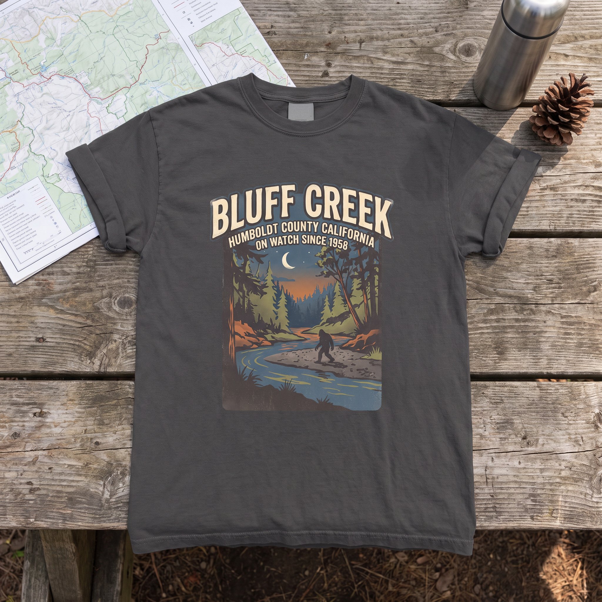 The Bluff Creek On Watch tee in graphite laid flat with field kit from the Bigfoot file