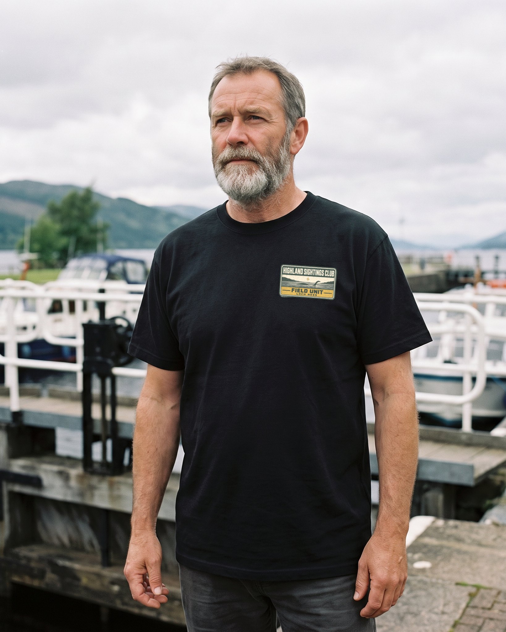 A person wearing the Highland Sightings Club tee in black on location near Loch Ness, Scotland