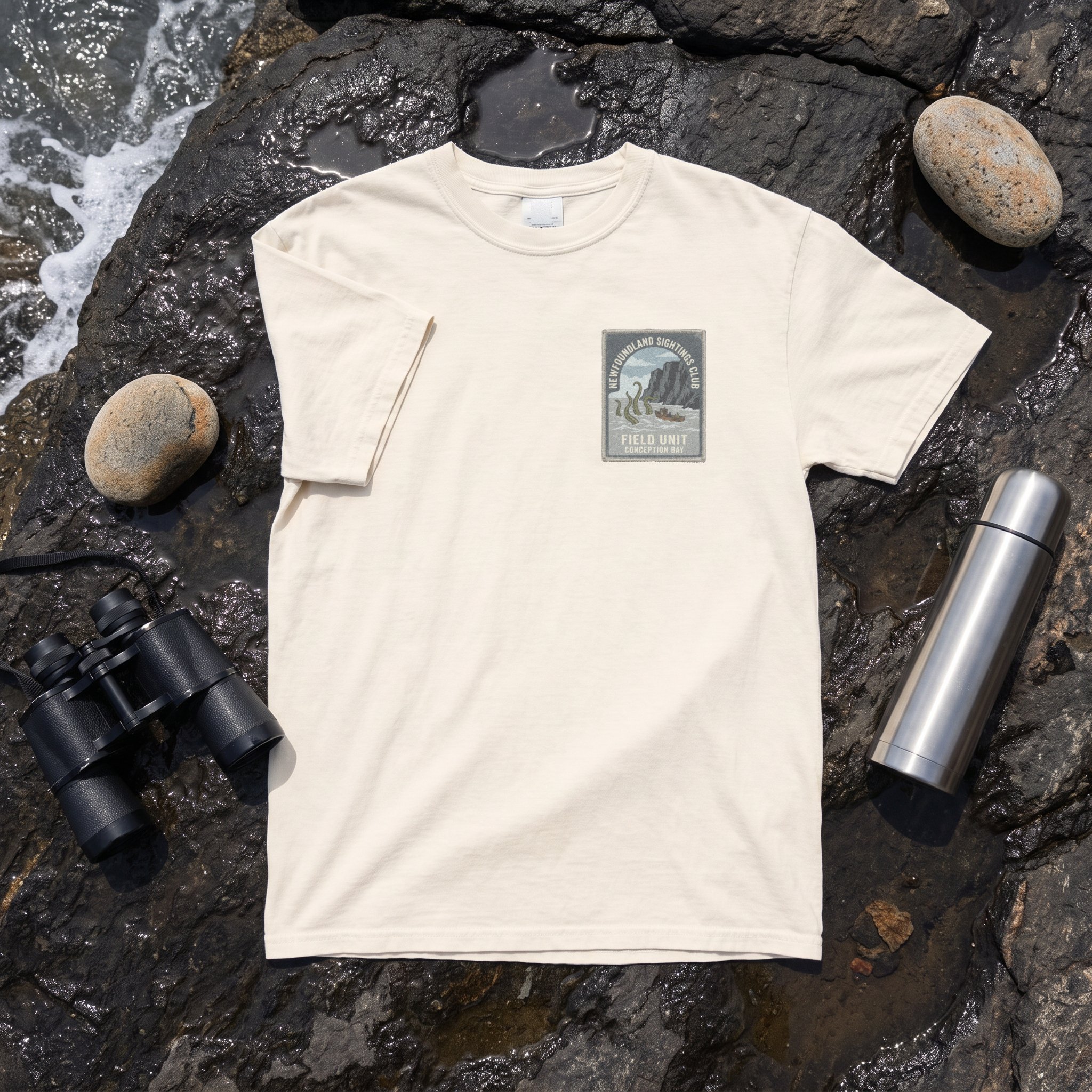 The Newfoundland Sightings Club tee in ivory laid flat with field kit from the Kraken file