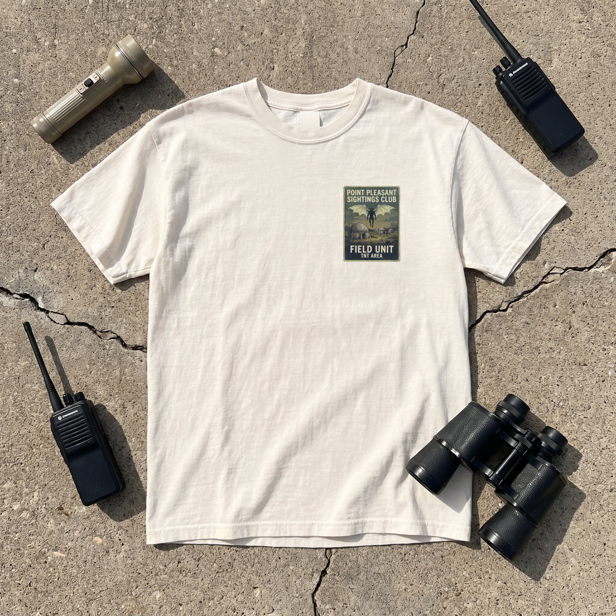 The Point Pleasant Sightings Club tee in ivory laid flat with field kit from the Mothman file