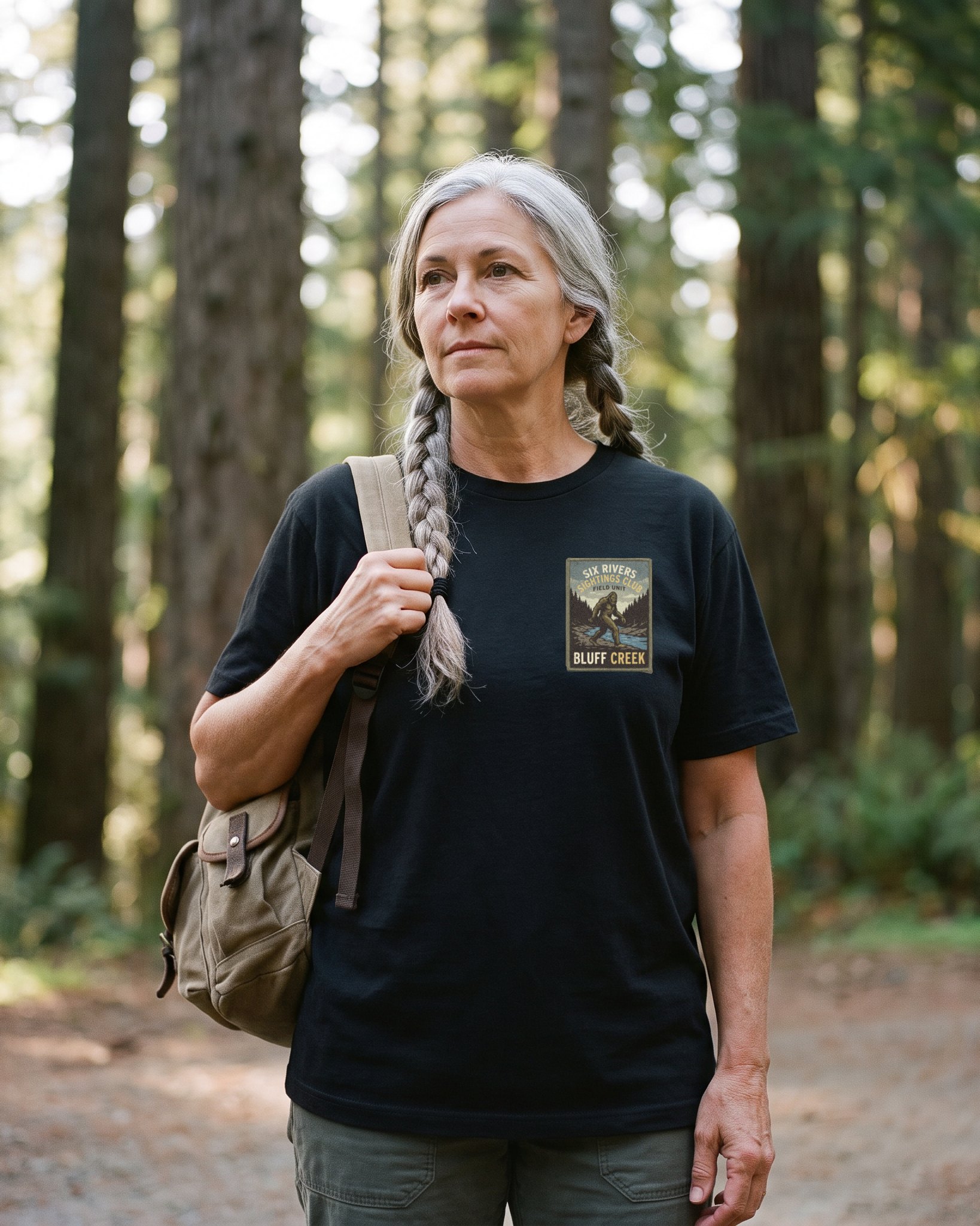 A person wearing the Six Rivers Sightings Club tee in black on location near Bluff Creek, California